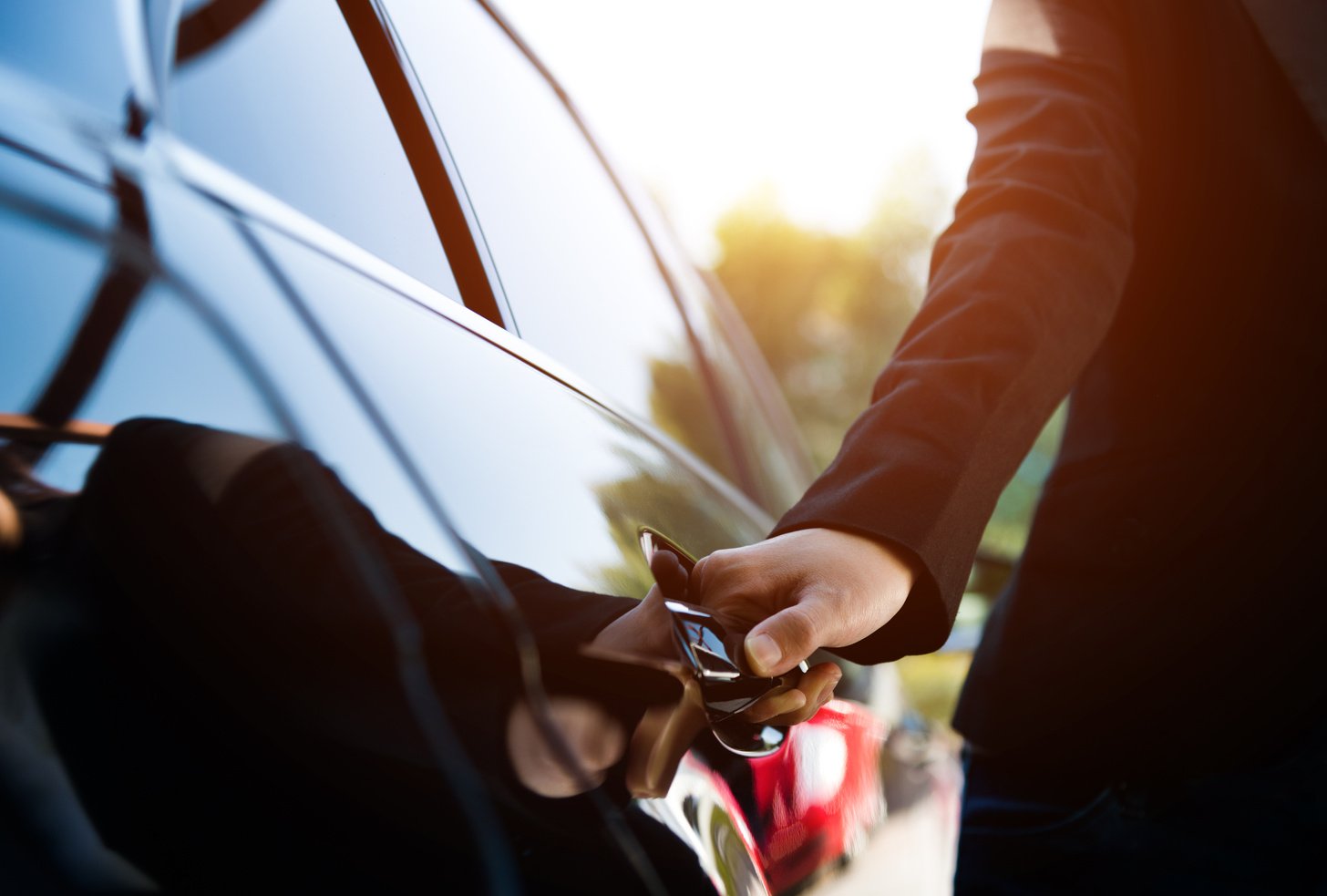 Female chauffeur opening a luxury car door